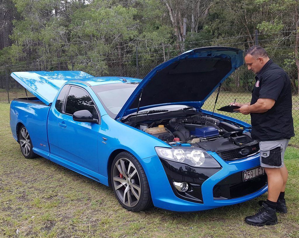 man infront of blue car doing inspection